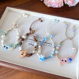 Detailed view of handmade ceramic beaded bracelets with cute animal charms and wax cord.
