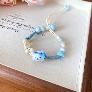 Detail of a cute ceramic cat charm bracelet with blue and white braided wax cord