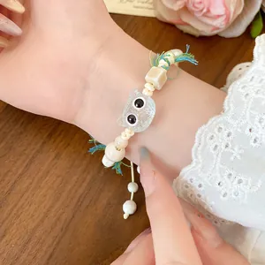 Close-up of a cute handmade ceramic cat charm bracelet on a wax cord with colorful beads