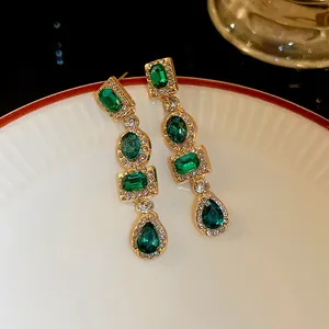 Dettaglio di orecchini retrò con cristalli verde smeraldo, placcatura in oro e strass luccicanti