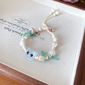 Detailed view of a handmade ceramic cat charm bracelet with colorful tassels and beads