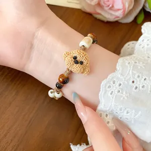 Close-up of a cute ceramic dog charm bracelet with tiger eye beads on a female wrist.