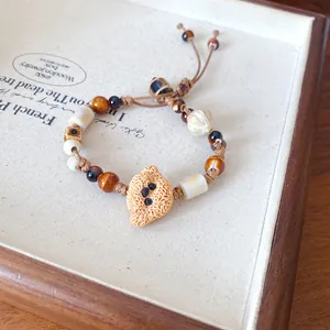 Detailed view of the textured ceramic animal charm and tiger's eye beads on a wax cord