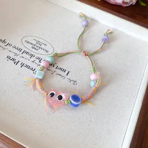 Detailed view of a cute colorful handmade ceramic cat beaded braided rope bracelet.