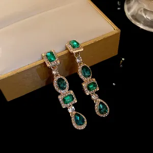 Vista dettagliata di orecchini vintage con cristalli verde smeraldo e diamanti incastonati.