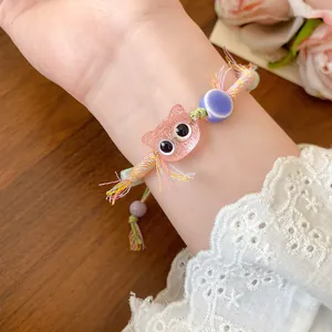 Close-up view of a colorful woven bead bracelet featuring a cute pink cat charm on wrist