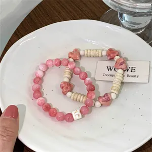 Dopamine style pink and white ceramic beaded bracelet with heart charms on a plate