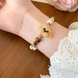 Close-up of a handmade ceramic puppy bead bracelet with tiger eye stones on a wrist