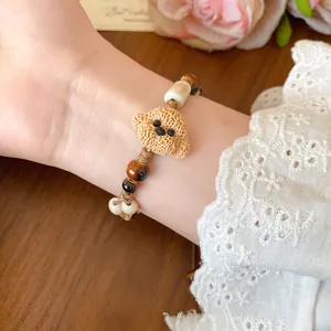 Detailed view of a cute ceramic dog beaded bracelet with brown wax cord on wrist