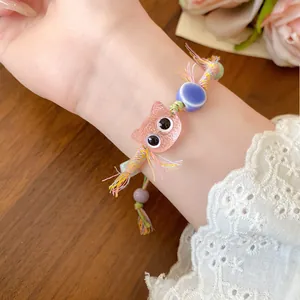 Detailed macro view of a colorful hand-woven bracelet with a cute pink cat charm