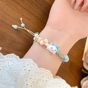 Close-up of a handmade ceramic cat beaded bracelet worn on a woman's wrist with lace sleeve