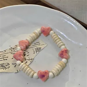 Detailed macro shot of pink ceramic heart beads and off-white disc charm bracelet