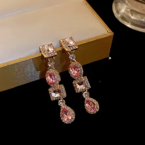 Dettaglio di orecchini pendenti con pietre rosa in stile palazzo vintage e strass