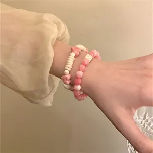 Detailed view of handmade pink and cream beaded bracelets with heart charms on a wrist