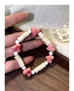 Detail macro shot of a handmade dopamine pink heart ceramic beaded bracelet for women