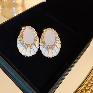Élégantes boucles d'oreilles blanches en forme de coquille avec zircons et aiguilles en argent
