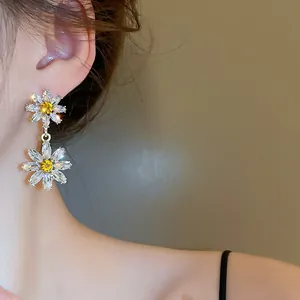 Gros plan sur d'élégantes boucles d'oreilles marguerites à deux niveaux en zircons jaunes.
