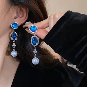 Detailed view of French vintage drop earrings featuring blue stones and elegant dangling pearls.