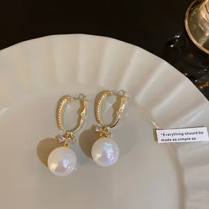 Detail shot of elegant gold earrings with bow design and iridescent mermaid pearl