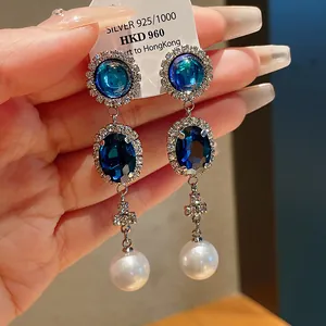 Elegant vintage-style dangle earrings with blue crystals and white pearls.