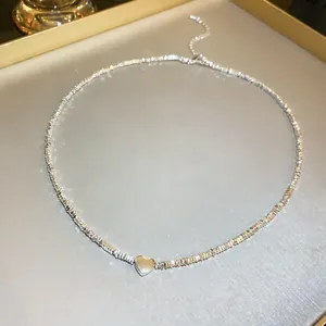 Close-up of a silver textured bead necklace featuring a polished heart pendant