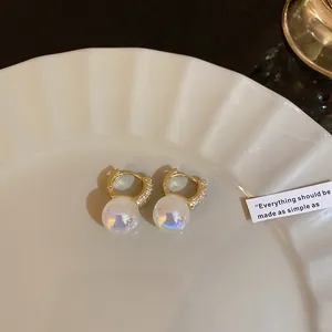 Macro view of mermaid pearl hoop earrings with crystal pavé and iridescent finish