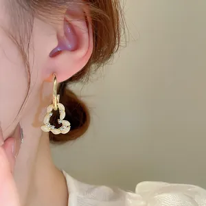Gros plan de boucles d'oreilles cœur dorées élégantes avec perles crème et zircons.