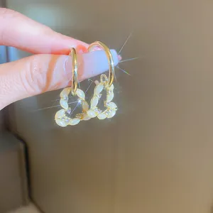 Gros plan de boucles d'oreilles créoles dorées avec breloques cœur en zircon