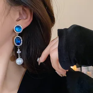 Detailed view of French retro earrings with blue gemstones and hanging white pearl