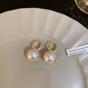 Detail view of elegant pearl earrings with sparkling diamond-encrusted gold settings