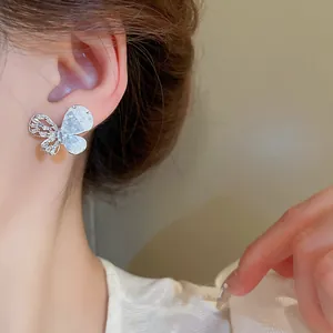 Détail d'une boucle d'oreille papillon en argent avec des accents de zircon sur l'oreille