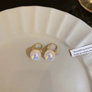 Close-up of elegant iridescent mermaid pearl drop earrings on a white decorative plate