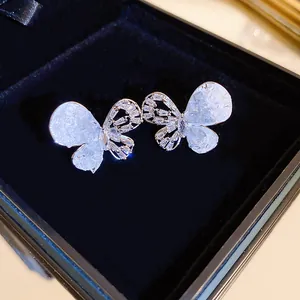 Gros plan de boucles d'oreilles papillon avec incrustation de zircon dans un écrin noir.