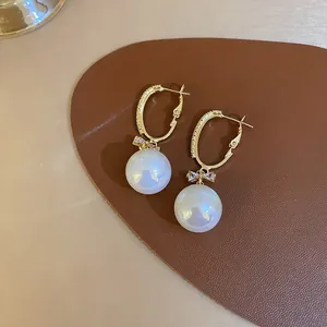 Detailed view of elegant mermaid pearl earrings with iridescent luster and crystal bow