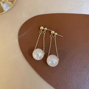 Close-up of mermaid pearl dangle earrings with iridescent luster and gold chain