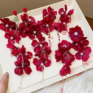 Detailed view of handmade red fabric flower earrings with faux pearls and teardrop charms