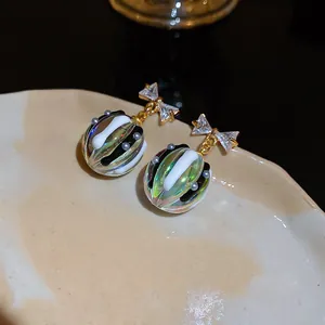 Gros plan de boucles d'oreilles nœud en zircon avec gouttes sphériques irisées