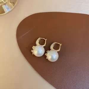 Close-up of elegant mermaid pearl earrings with gold-plated rhinestone details