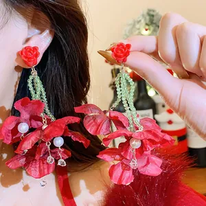 Stunning detail of red fabric flower earrings featuring pearls and green crystal beads