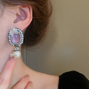 Gros plan d'une boucle d'oreille vintage avec pierre rose et perle sur l'oreille