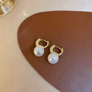 Macro detail view of iridescent mermaid pearl hoop earrings with crystal pavé gold finish