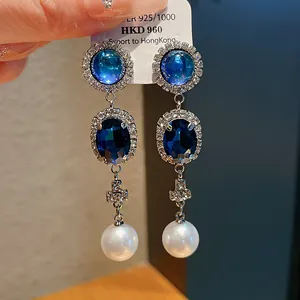 Detail of French retro earrings featuring blue crystals and white round hanging pearls