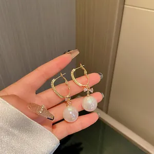 Close-up of elegant mermaid pearl earrings with dainty crystal bow detail