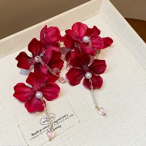 Close-up of red fabric flower earrings with pearls and heart-shaped drops
