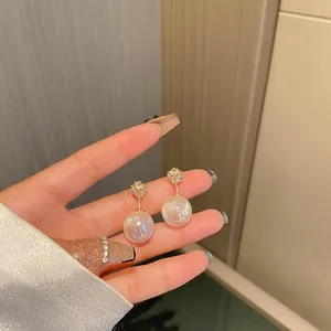 Close-up view of iridescent mermaid pearl drop earrings with sparkling crystal studs