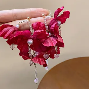 Macro view of handmade red fabric flower earrings featuring elegant pearls and heart drops