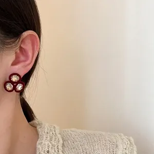 Gros plan de boucles d'oreilles vintage rouges avec trois strass étincelants de luxe.
