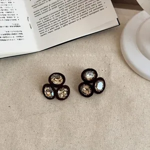Gros plan de boucles d'oreilles vintage floquées marron avec strass sur tissu texturé.