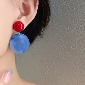 Eleganti orecchini a perno rotondi in acrilico rosso e blu su modella asiatica