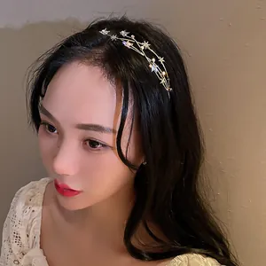 Close-up of a sparkling star and pearl headband worn by a model in warm light
